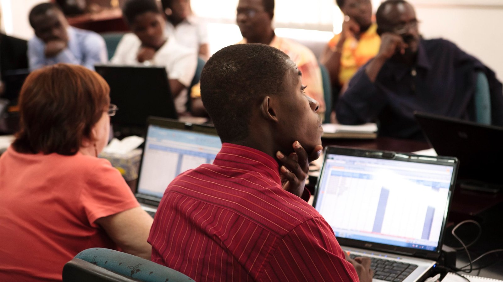 Participants at a business accounting training working through spreadsheets on laptops